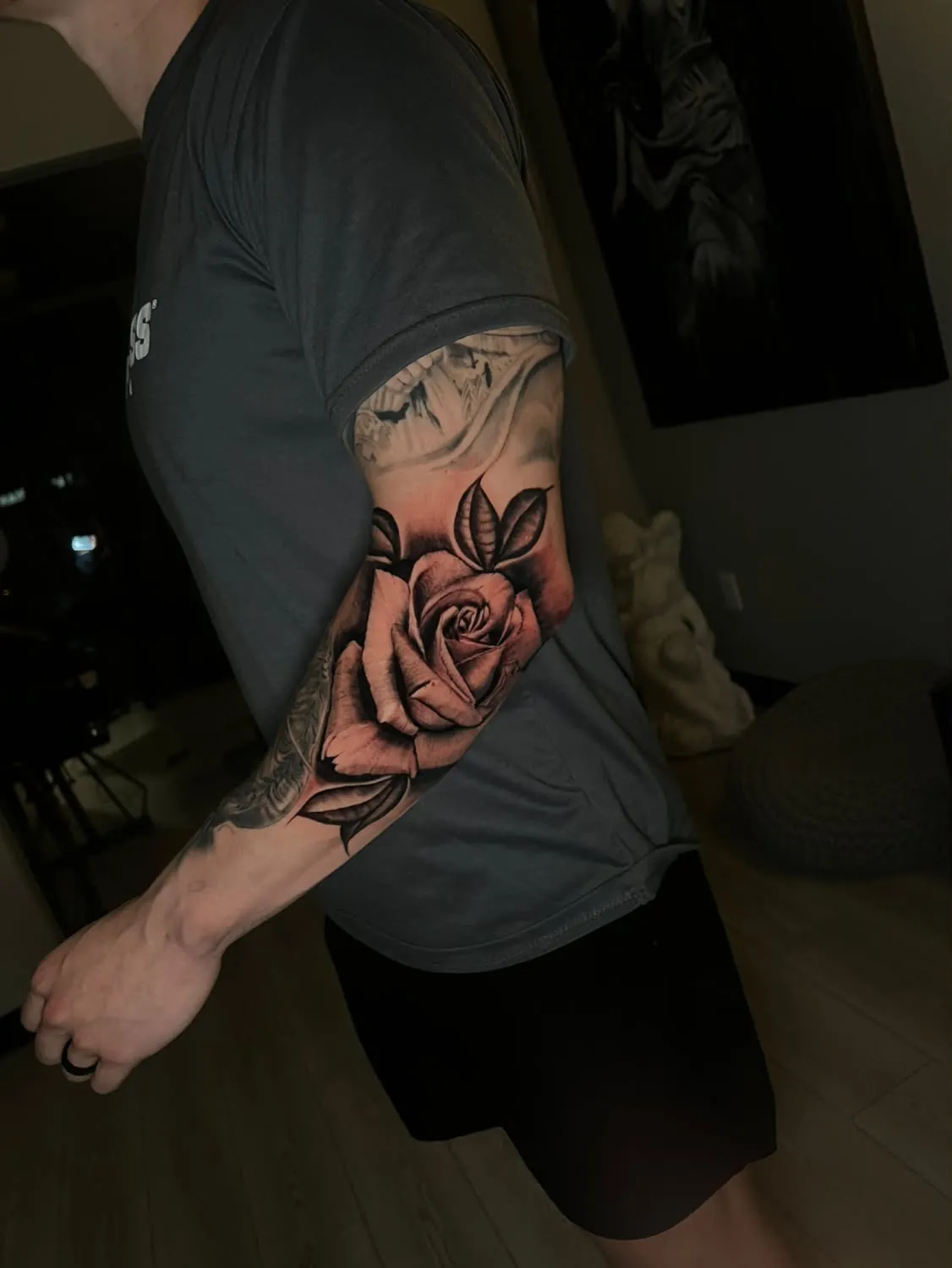 Black-and-gray rose with shaded leaves wrapping the elbow, joining existing arm work